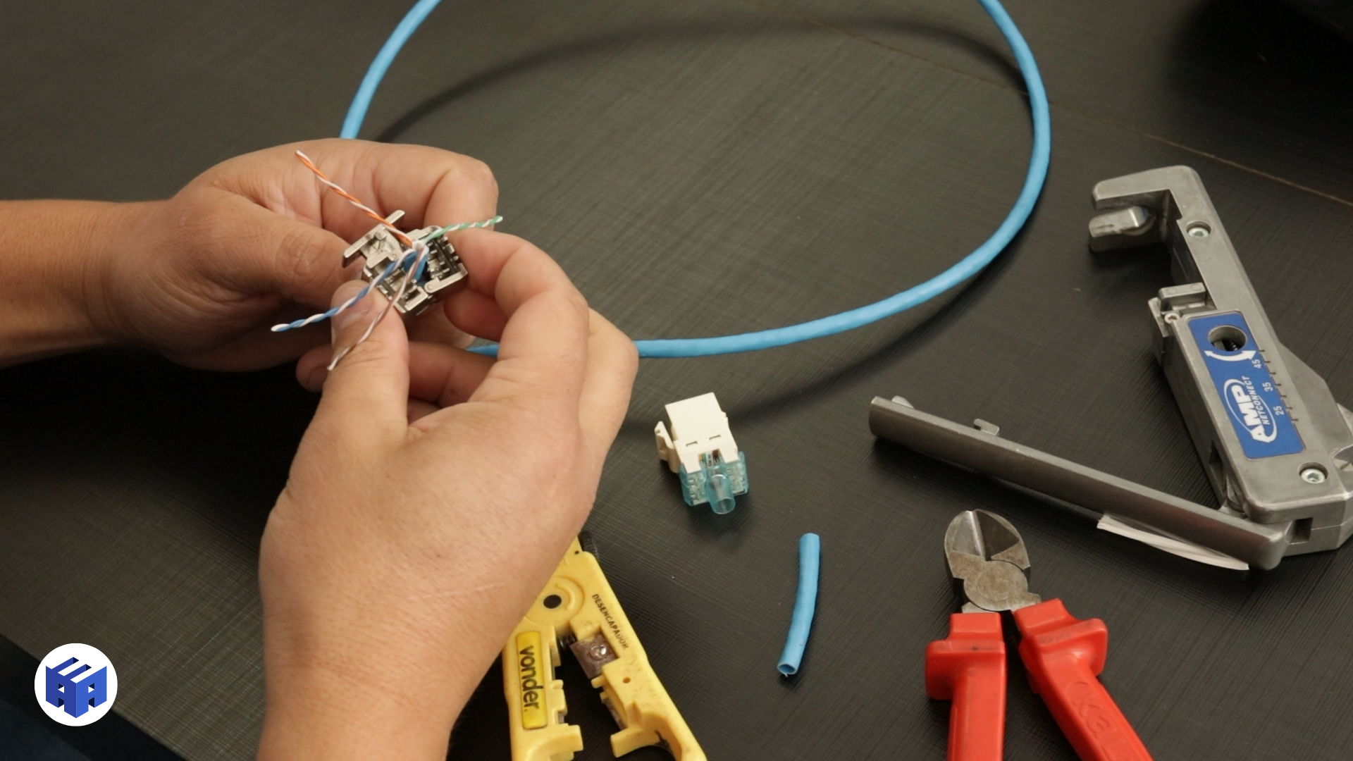 Foto mostrando o processo de crimpagem de um cabo TP Cat6a. O profissional utiliza um conector específico e ferramentas de crimpagem para fixar os fios ao conector, garantindo uma conexão segura e confiável no sistema de cabeamento estruturado.