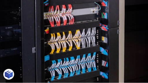 Imagem de um rack de rede com cabeamento estruturado, mostrando várias fileiras de cabos de rede organizados horizontalmente em painéis de conexão. Os cabos estão agrupados por cores, como vermelho, azul e amarelo, indicando diferentes funções ou redes dentro do sistema. A organização dos cabos reflete uma instalação profissional e bem planejada, ideal para ambientes corporativos e comerciais onde a performance e a flexibilidade da rede são essenciais.