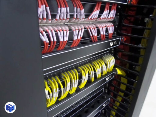 Imagem de um rack de cabeamento estruturado, exibindo patch panels com cabos de rede categorizados e etiquetados. A instalação demonstra uma infraestrutura de cabeamento de rede bem planejada e eficiente, com cabos de diferentes cores para fácil identificação e manutenção, refletindo as melhores práticas em gestão de cabos de rede e TI.