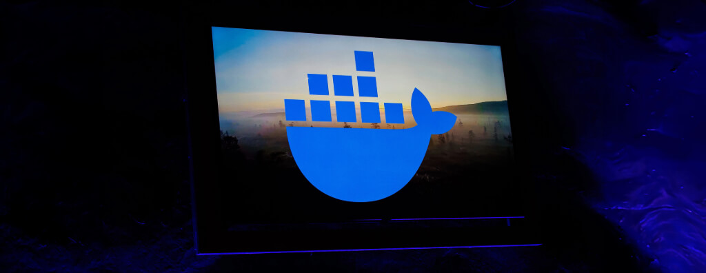 Imagem com o logotipo do Docker, representado por uma baleia azul carregando contêineres, destacando um conceito visual que remete ao empacotamento e transporte eficiente de aplicações em contêineres. Entenda 'o que é Docker' e como ele transforma o desenvolvimento de software ao oferecer portabilidade e eficiência.